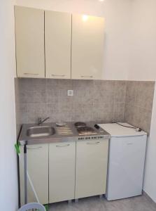 una cocina con armarios blancos y fregadero en Mica apartmani, en Sutomore