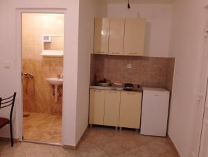 a small kitchen with white cabinets and a sink at Mica apartmani in Sutomore +9 photos