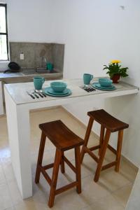 eine Küche mit einer Theke mit zwei Stühlen und einem Tisch in der Unterkunft Xula Bacalar in Bacalar
