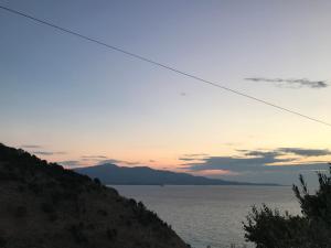 a sunset over the water with a hill at Vila Bedro in Sarandë