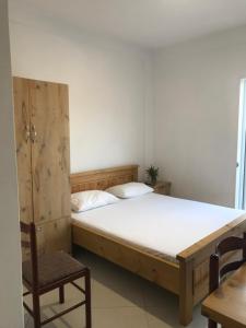 a bedroom with a wooden bed and a chair at Vila Bedro in Sarandë