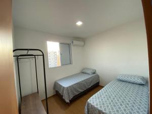 a small room with two beds and a window at Apartamento com Sacada na Gleba, Novo e equipado in Londrina