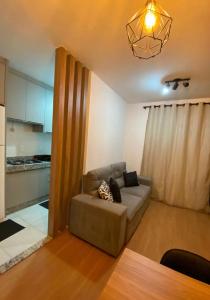 a living room with a couch and a kitchen at Apartamento com Sacada na Gleba, Novo e equipado in Londrina