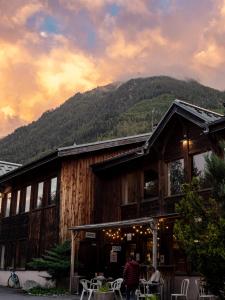 un bâtiment avec des personnes assises à l'extérieur avec une montagne dans l'établissement Auberge de Jeunesse HI Chamonix, à Chamonix-Mont-Blanc
