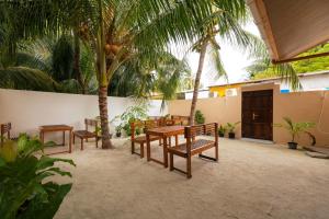 a patio with a table and benches and palm trees at Vacanza Mathiveri in Mathiveri
