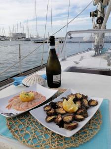 a bottle of wine and a plate of food on a boat at La tua stanza a vela sul mare in Bari