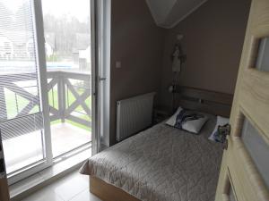 a small bedroom with a bed and a large window at apartament Jaśkowy in Żarnowska