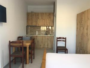 a kitchen with wooden cabinets and a table and chairs at Vila Bedro in Sarandë