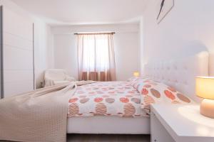 a white bedroom with a bed and a chair at Apartmani Xenia & Desiderio in Buzet