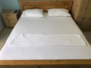 a large bed with white sheets and pillows on it at Vila Bedro in Sarandë