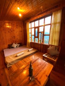 1 dormitorio en una cabaña de madera con cama y mesa en Pine Tower Inn, en Manali