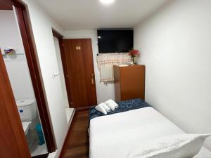 een kleine kamer met een bed en een televisie bij Hostal Casa del Café in Bogota