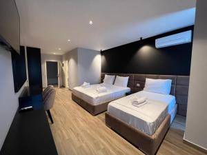 una camera d'albergo con due letti e un divano di Hotel LEON - Beach Front a Shëngjin
