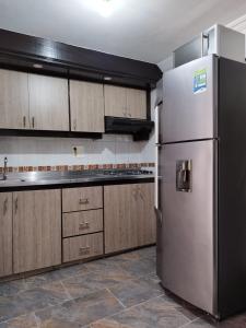 a kitchen with a stainless steel refrigerator and wooden cabinets at Apartamento Quintas de San Javier in Medellín