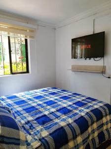 a bedroom with a bed and a tv on the wall at Apartamento Quintas de San Javier in Medellín