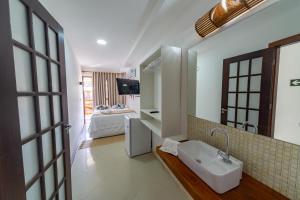 a bathroom with a sink and a room with a bed at Praia do Forte Suites in Praia do Forte