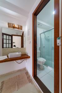 a bathroom with a sink and a glass shower at Praia do Forte Suites in Praia do Forte