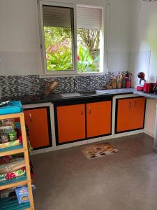 a kitchen with orange cabinets and a window at Bas de Villa ALPINIA au Gosier in Le Gosier