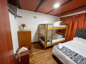 a room with two beds and a bunk bed at Hostal Casa del Café in Bogotá