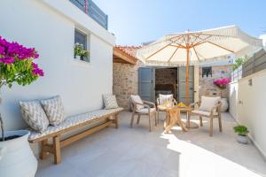 een patio met een tafel en stoelen en een parasol bij The Violin House in Chania