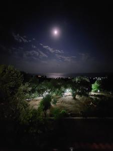 luna llena elevándose sobre una playa por la noche en Daphne Studios, en Marathokampos