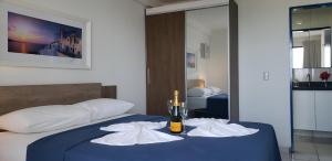 1 dormitorio con 1 cama con 1 botella de vino y toallas en Natal Prime - Porto Imperial en Natal