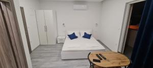 a small bedroom with a white bed with blue pillows at Apartments Dado in Baška Voda