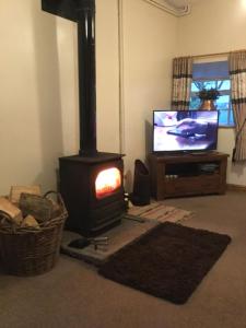 a living room with a stove and a television at Cosy Rural Cottage Peak District, Pets Welcome in Hollinsclough