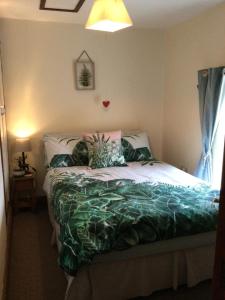 a bedroom with a bed with a green comforter at Cosy Rural Cottage Peak District, Pets Welcome in Hollinsclough
