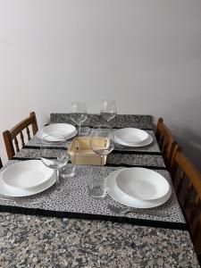 een tafel met witte borden en wijnglazen erop bij Ático en Boiro La Niña, a 50m. Playa Jardín. in Boiro