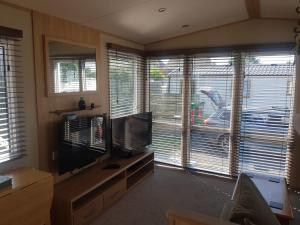 een woonkamer met een flatscreen-tv en 2 ramen bij 6 Berth Caravan on Lakeside Holiday Park in Burnham on Sea