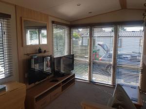 a living room with a flat screen tv and two windows at 6 Berth Caravan on Lakeside Holiday Park in Burnham on Sea