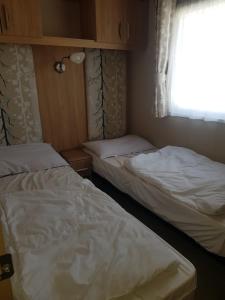 two beds in a small room with a window at 6 Berth Caravan on Lakeside Holiday Park in Burnham on Sea