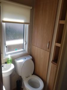 a small bathroom with a toilet and a window at 6 Berth Caravan on Lakeside Holiday Park in Burnham on Sea