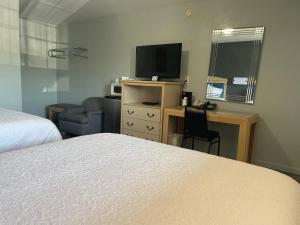 Una habitación de hotel con una cama y un escritorio con televisión. en Stratford Inn, en Stratford