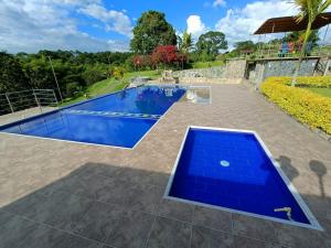 una piscina en un patio trasero con una piscina azul en Hotel Campestre Los Mangos, en Quimbaya