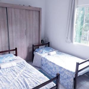 two beds sitting in a room with a window at Recanto Sananda in São José dos Pinhais