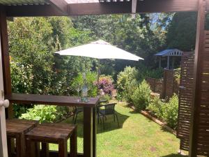a table with a white umbrella in a garden at Burradoo Studio in Leura