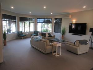 a living room with couches and a flat screen tv at Palm Paradise in Tauranga