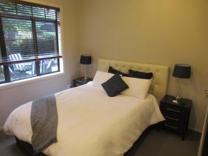 Un dormitorio con una cama blanca con almohadas y una ventana en Palm Paradise en Tauranga