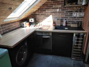 a kitchen with a sink and a washing machine at La cachette sous les toits balnéo climatisé in Nantes