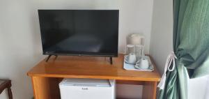 une télévision assise sur un support en bois avec une table dans l'établissement Casa Felicidade, à Lagos