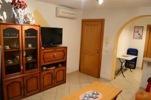 a living room with a television and a wooden cabinet at Guest House Suzana in Omišalj