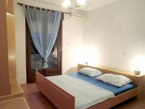 um quarto com uma cama com lençóis azuis e uma janela em Apartments for families with children Banjol, Rab - 16645 em Rab