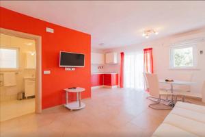 ein Wohnzimmer mit einer roten Wand und einem Tisch in der Unterkunft Family friendly seaside apartments Stanici, Omis - 16606 in Omiš