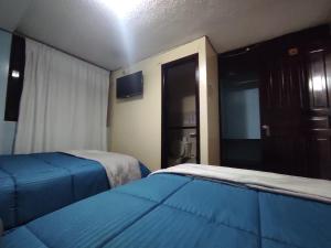 a hotel room with two beds and a television at Hostal Buenaventura Ibarra in Ibarra