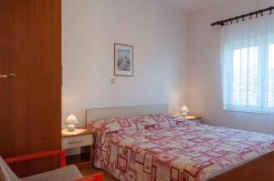 a bedroom with a bed and two tables and a window at Apartments by the sea Supetarska Draga - Gonar, Rab - 16738 in Rab