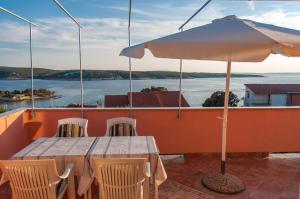 a table and chairs with an umbrella on a balcony at Apartments by the sea Supetarska Draga - Gonar, Rab - 16738 in Rab
