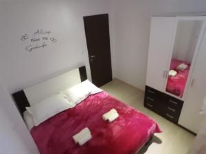una camera da letto con un letto con una coperta rossa e uno specchio di Apartments by the sea Podstrana, Split - 16793 a Podstrana