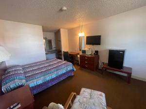 a hotel room with a bed and a flat screen tv at Riverside Inn in Glendive